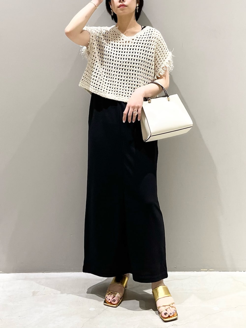 ホワイト系のショルダーバッグ、ブラック系のジャンパースカート、ゴールド系のサンダルを着用したレディースの夏コーディネートの4枚目の写真