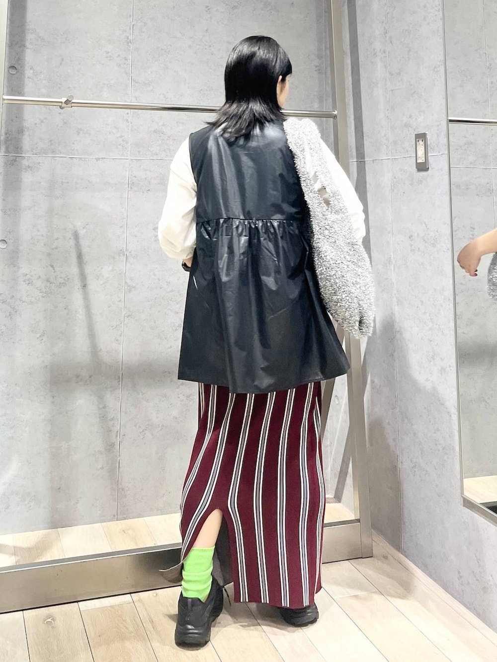 シルバー系のショルダーバッグ、レッド系のスカート、ブラック系のワンピースを着用したレディースの秋コーディネートの3枚目の写真