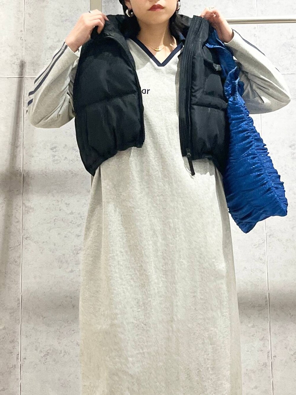 ブラック系のスニーカー、ブルー系のトートバッグ、ブラック系のベストを着用したレディースの冬コーディネートの4枚目の写真