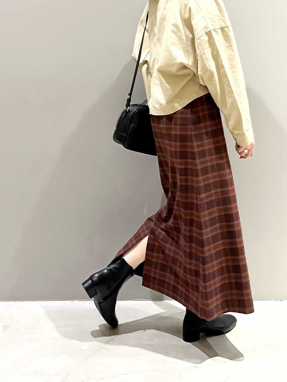 ブラック系のブーツ、レッド系のスカート、ブラック系のバッグを着用したレディースの秋コーディネートの3枚目の写真