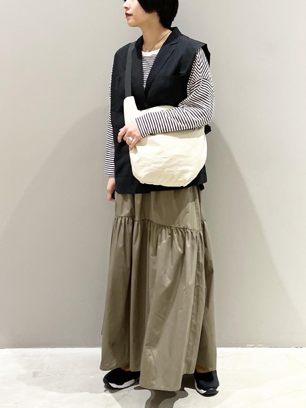 グリーン系のスカート、ブラック系のスニーカー、ホワイト系のショルダーバッグを着用したレディースの春コーディネートの4枚目の写真