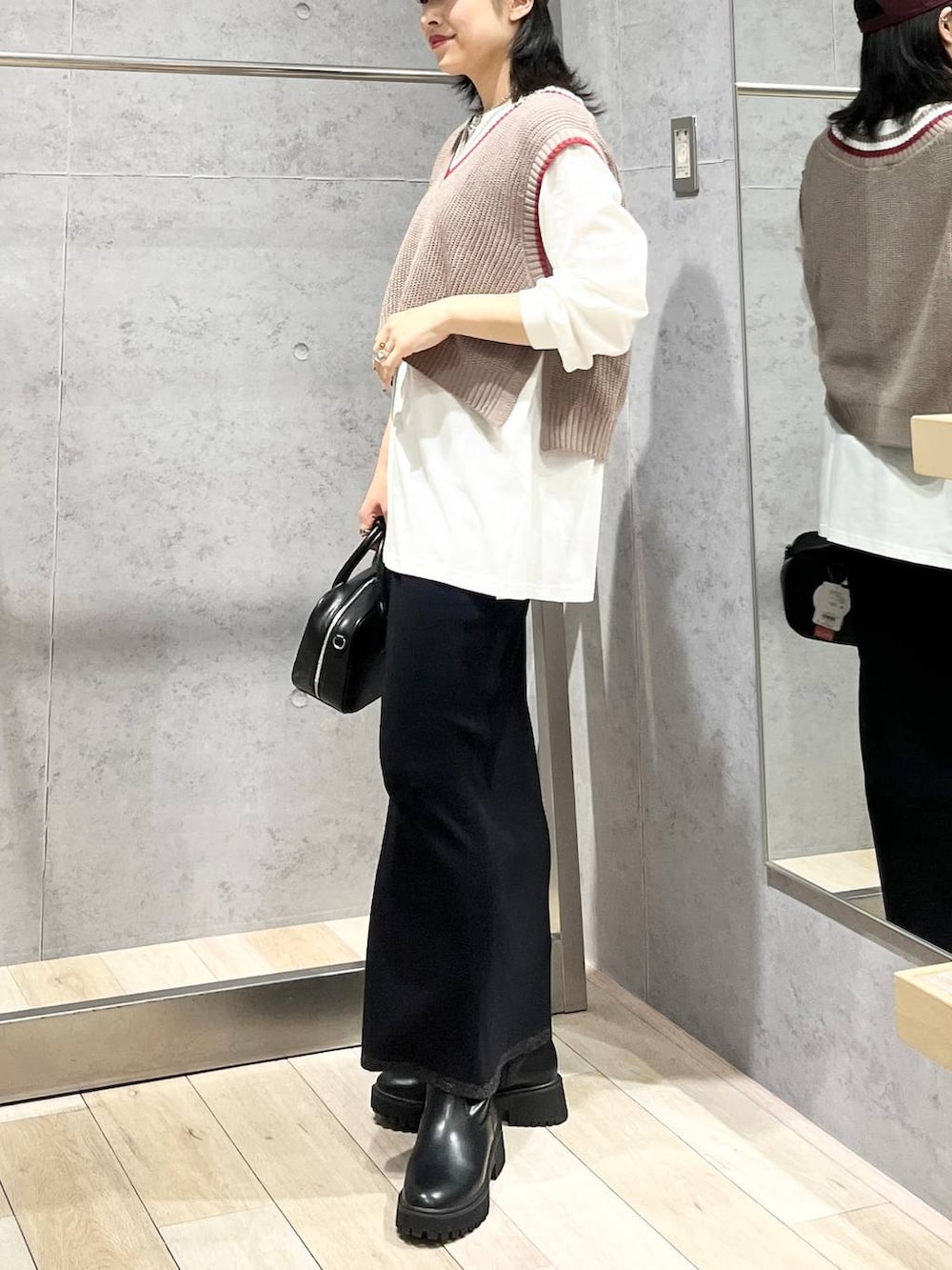 ブラック系のボストンバッグ、ブラック系のブーツ、ブラック系のスカートを着用したレディースの秋コーディネートの3枚目の写真