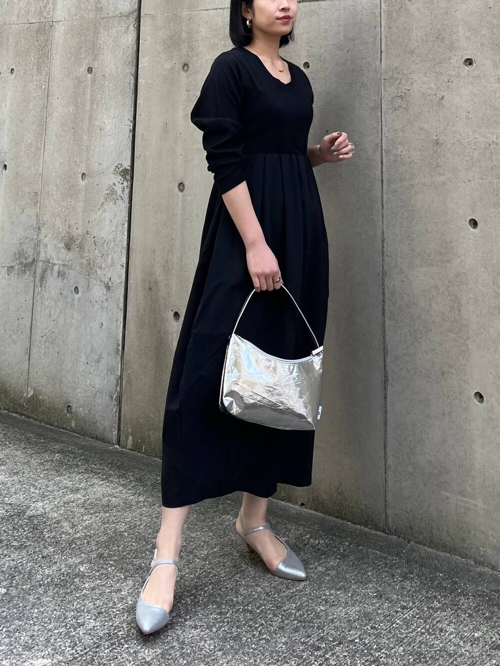 シルバー系のハンドバッグ、ブラック系のワンピース、グレー系のパンプスを着用したレディースの冬コーディネートの3枚目の写真