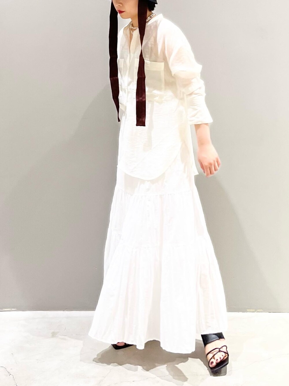 ホワイト系のスカート、ホワイト系のシャツ/ブラウス、ブラック系のサンダルを着用したレディースの夏コーディネートの4枚目の写真