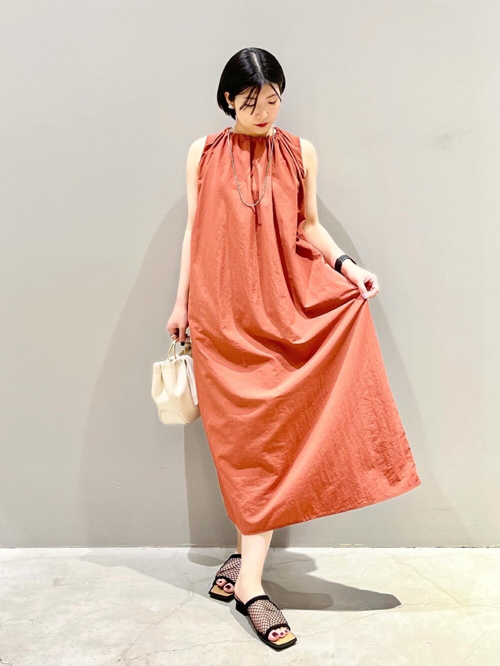 ブラウン系のワンピース、ホワイト系のバッグ、ブラック系のサンダルを着用したレディースの夏コーディネートの2枚目の写真