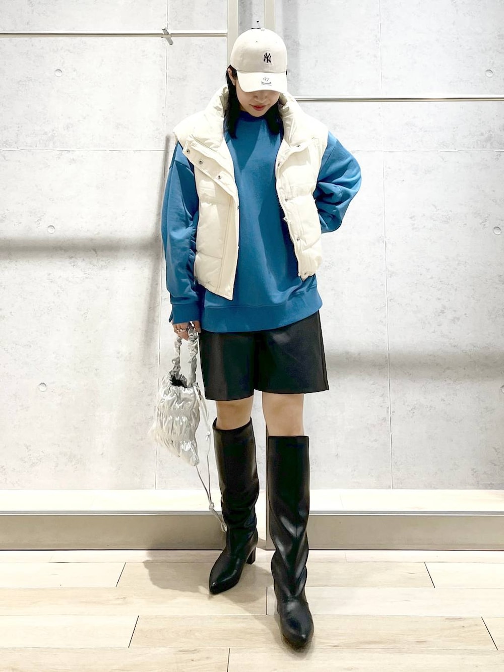 ホワイト系のダウンベスト、シルバー系のショルダーバッグ、ブラック系のその他パンツを着用したレディースの冬コーディネートの2枚目の写真