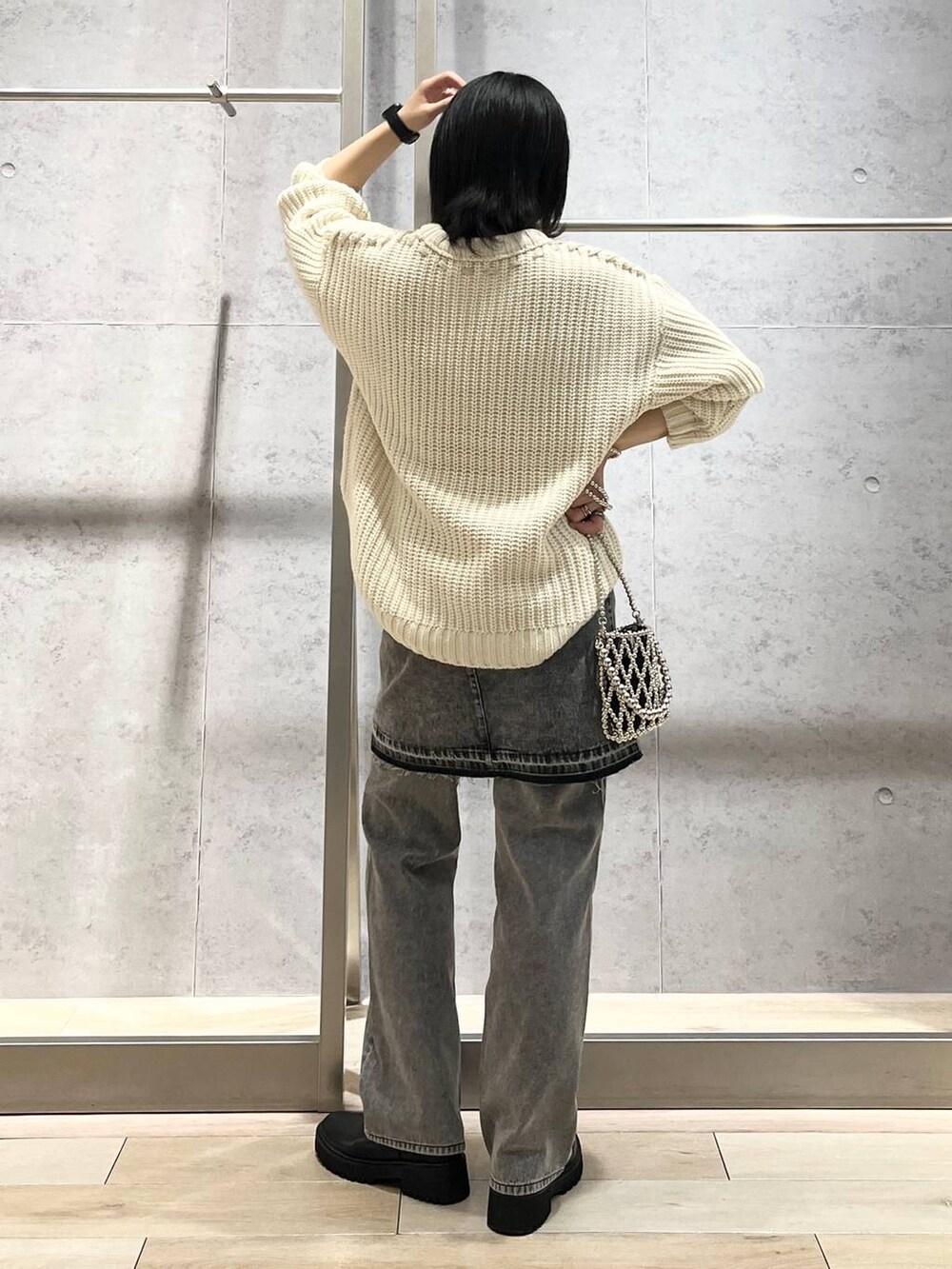 シルバー系のショルダーバッグ、ブラック系のデニムパンツ、ブラック系のブーツを着用したレディースの秋コーディネートの2枚目の写真