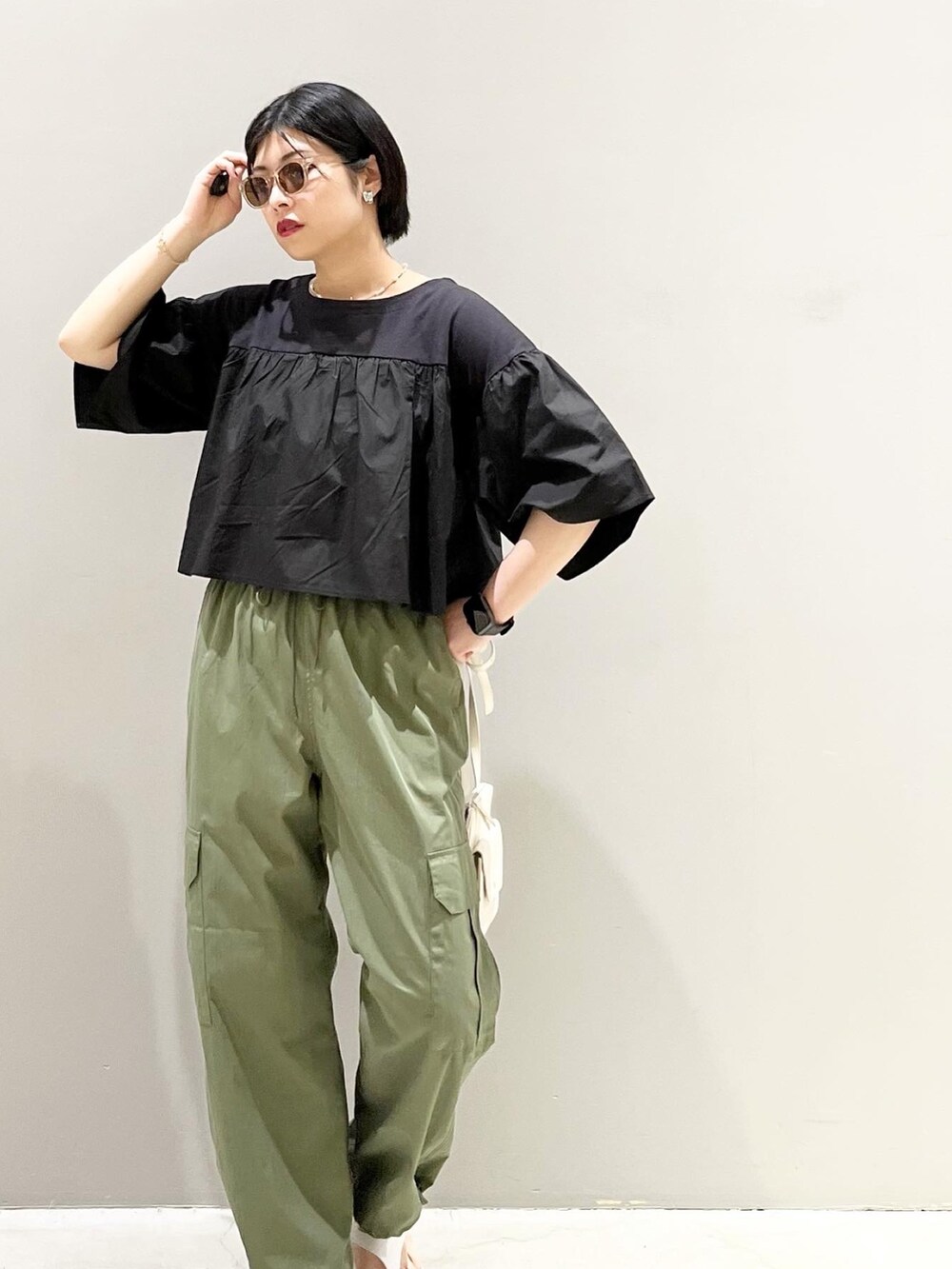 グリーン系のパンツ、ブラック系のTシャツ/カットソー、ホワイト系のショルダーバッグを着用したレディースの春コーディネートの5枚目の写真