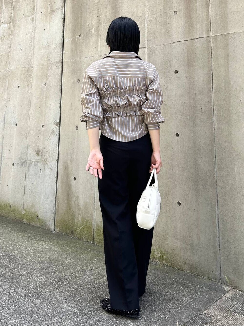 ブラック系のパンプス、ブラック系のその他パンツ、ホワイト系のボストンバッグを着用したレディースの秋コーディネートの2枚目の写真