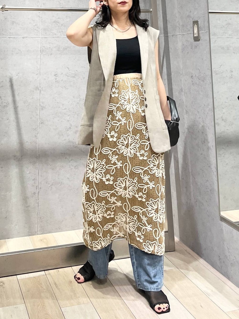 ブルー系のデニムパンツ、ブラック系のハンドバッグ、ブラック系のサンダルを着用したレディースの春コーディネートの6枚目の写真