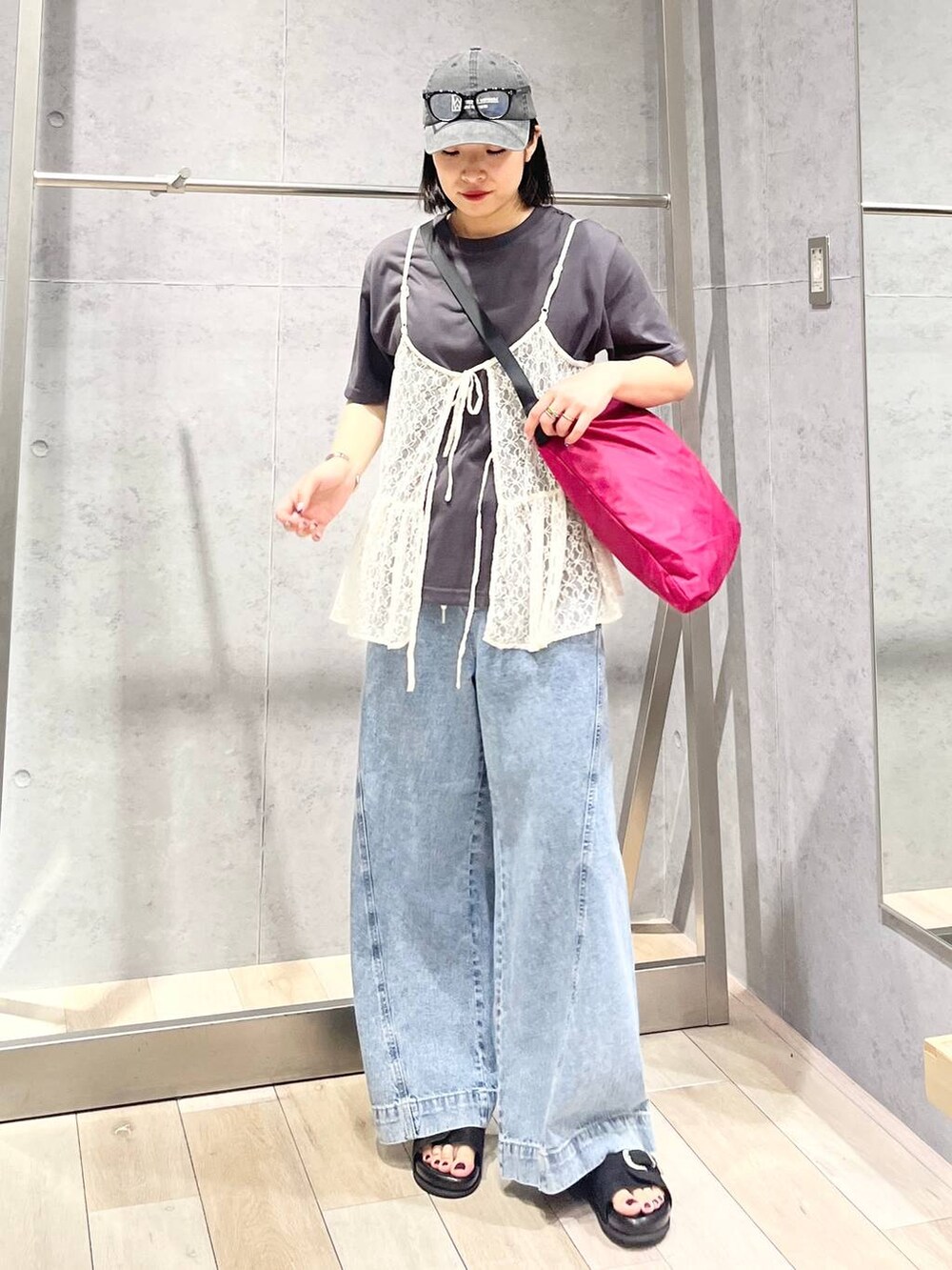 ブルー系のデニムパンツ、ブラック系のサンダル、ピンク系のショルダーバッグを着用したレディースの夏コーディネートの3枚目の写真