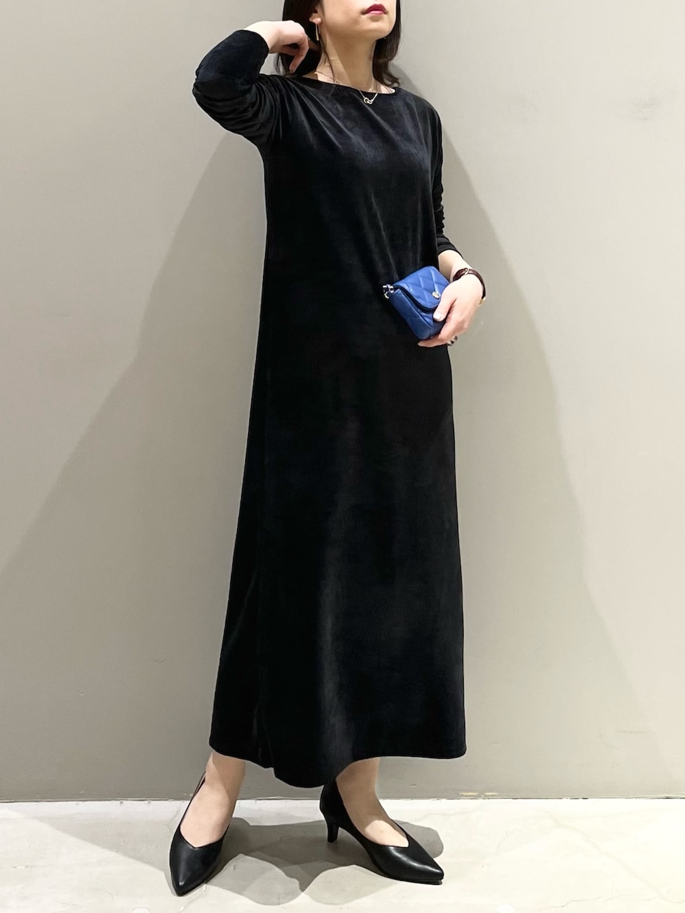 ブラック系のワンピース、ブルー系のショルダーバッグ、ブラック系のパンプスを着用したレディースの冬コーディネートの2枚目の写真