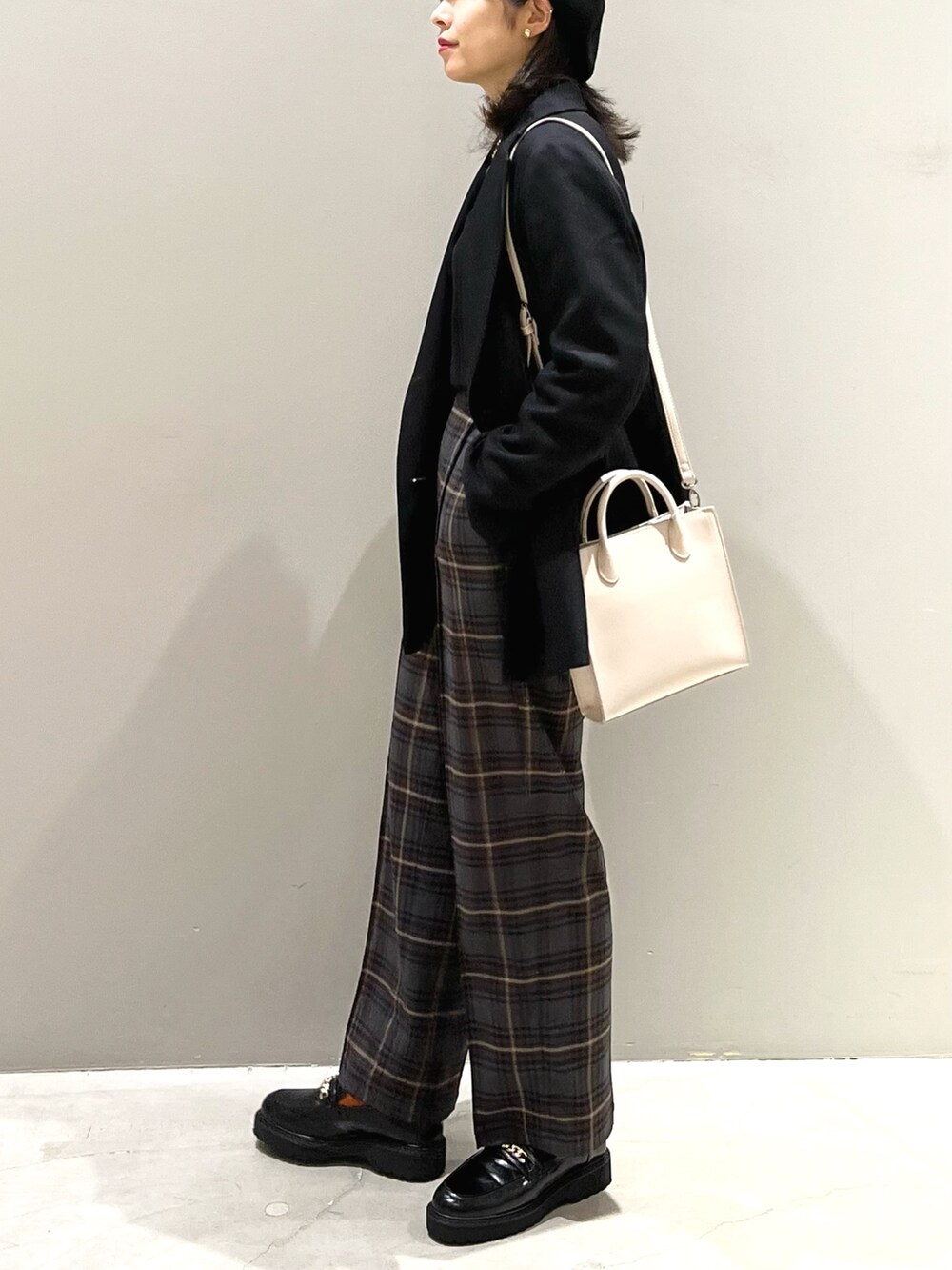 ブラウン系のスラックス、ブラック系のローファー、ホワイト系のショルダーバッグを着用したレディースの秋コーディネートの3枚目の写真
