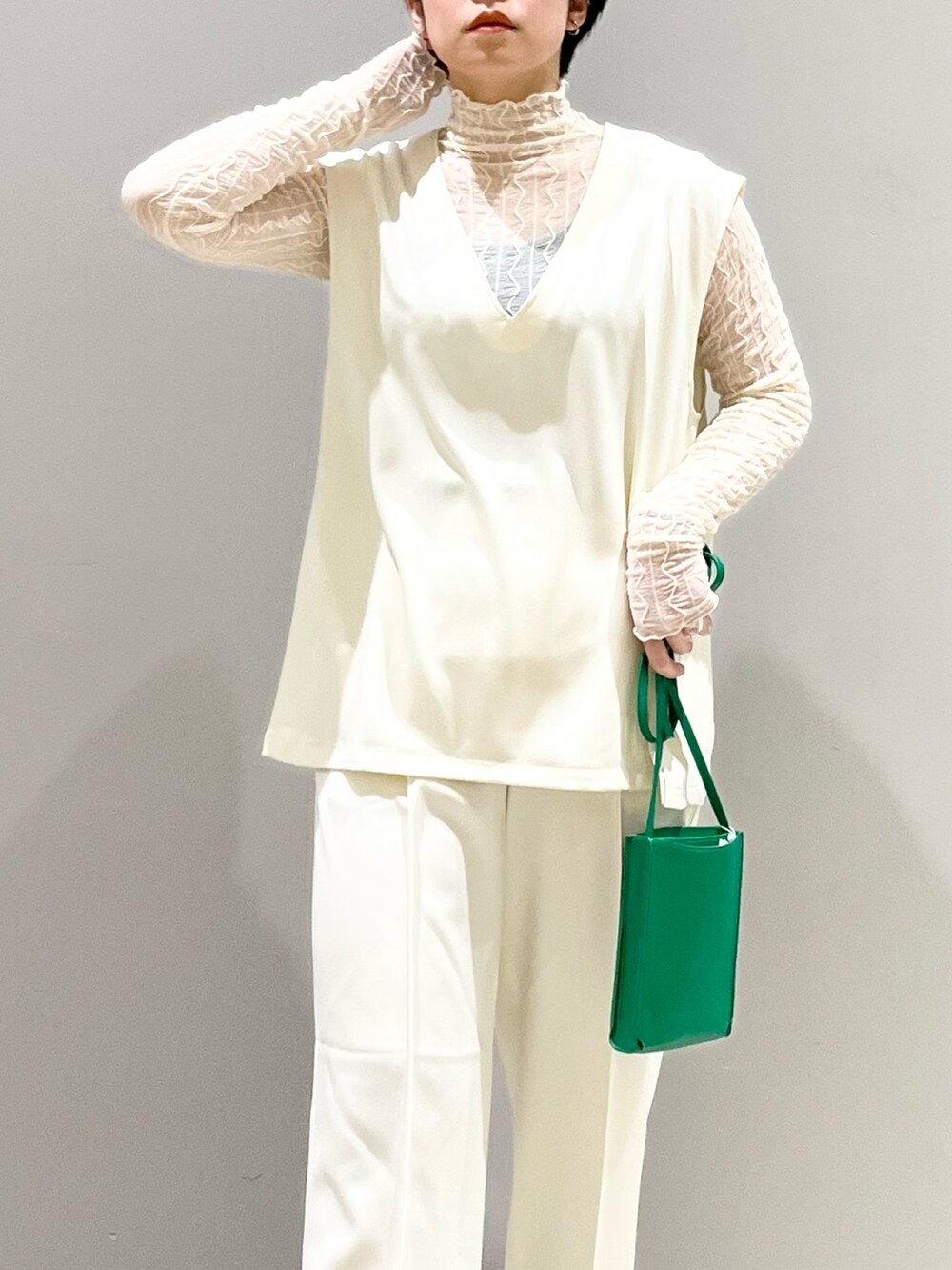 ホワイト系のベスト、グレー系のシューズ、グリーン系のバッグを着用したレディースの夏コーディネートの8枚目の写真