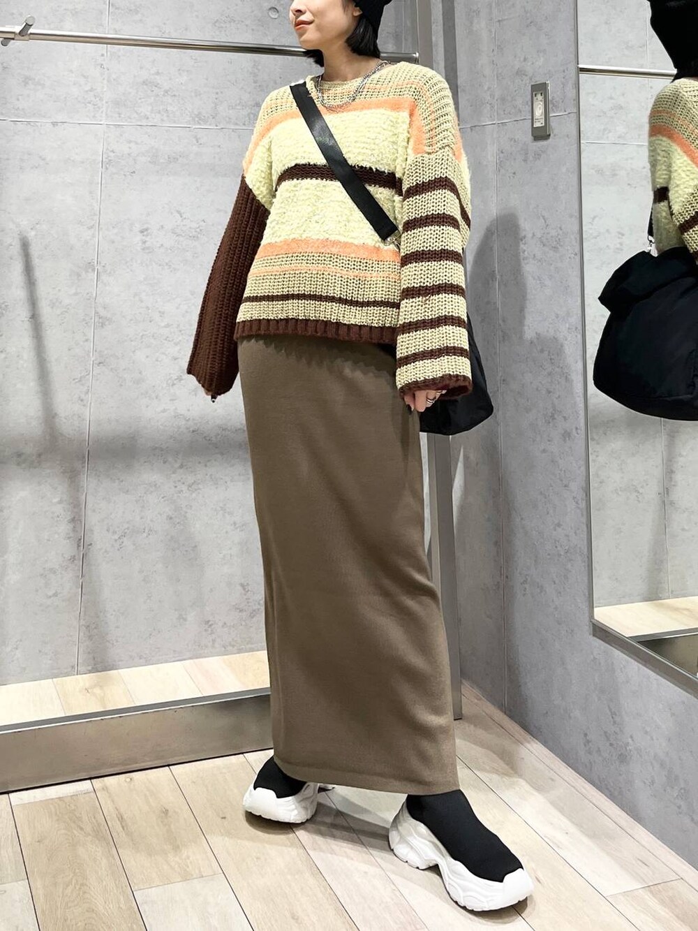 ブラウン系のスカート、ブラウン系のニット/セーター、ブラック系のブーツを着用したレディースの秋コーディネートの2枚目の写真