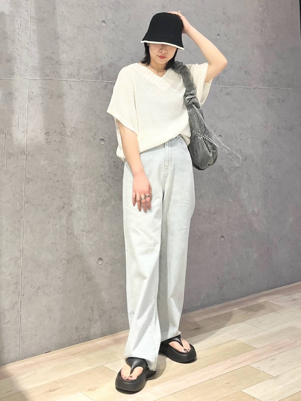 ブラック系のサンダル、ブルー系のデニムパンツ、ホワイト系のニット/セーターを着用したレディースの夏コーディネートの2枚目の写真