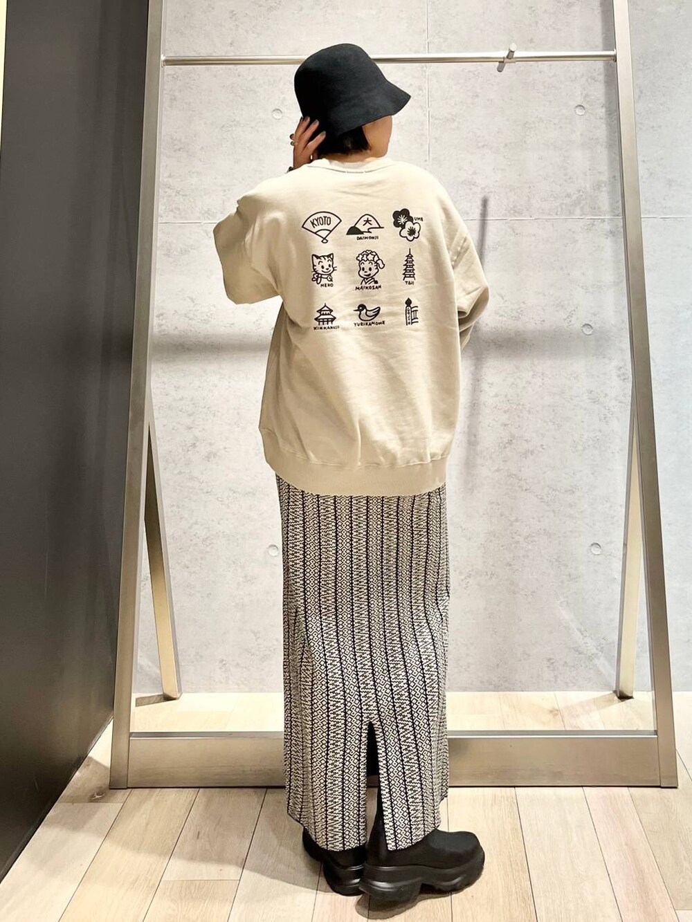 ブラック系のスカート、シルバー系のショルダーバッグ、ブラック系のブーツを着用したレディースの冬コーディネートの2枚目の写真