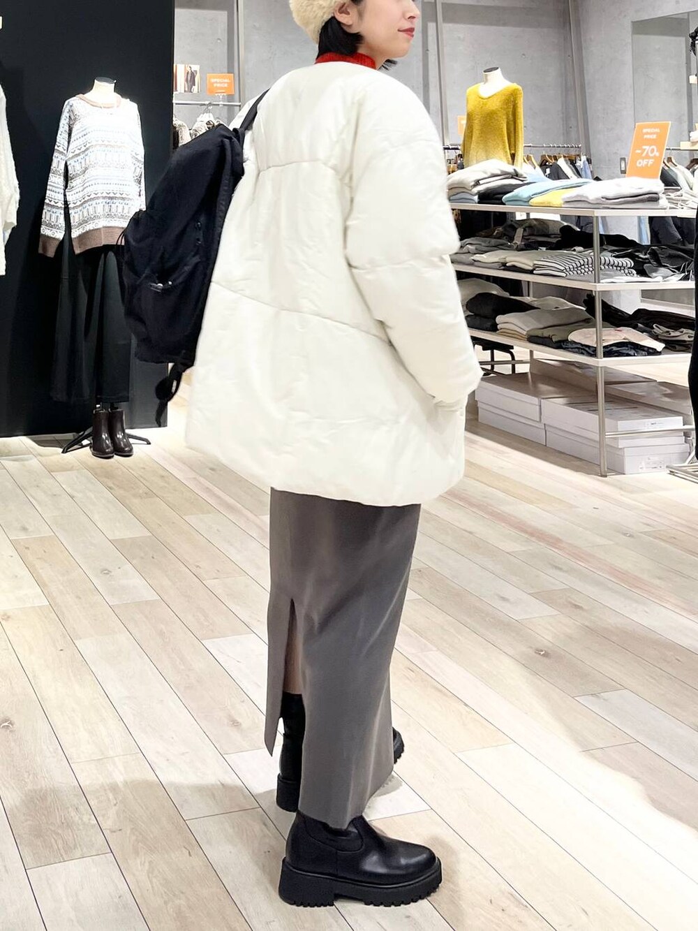 レッド系のニット/セーター、グレー系のスカート、ブラック系のブーツを着用したレディースの冬コーディネートの6枚目の写真