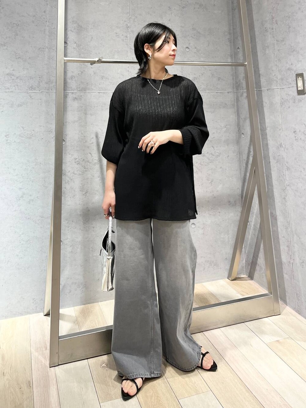 シルバー系のハンドバッグ、ブラック系のサンダル、グレー系のデニムパンツを着用したレディースの春コーディネートの6枚目の写真