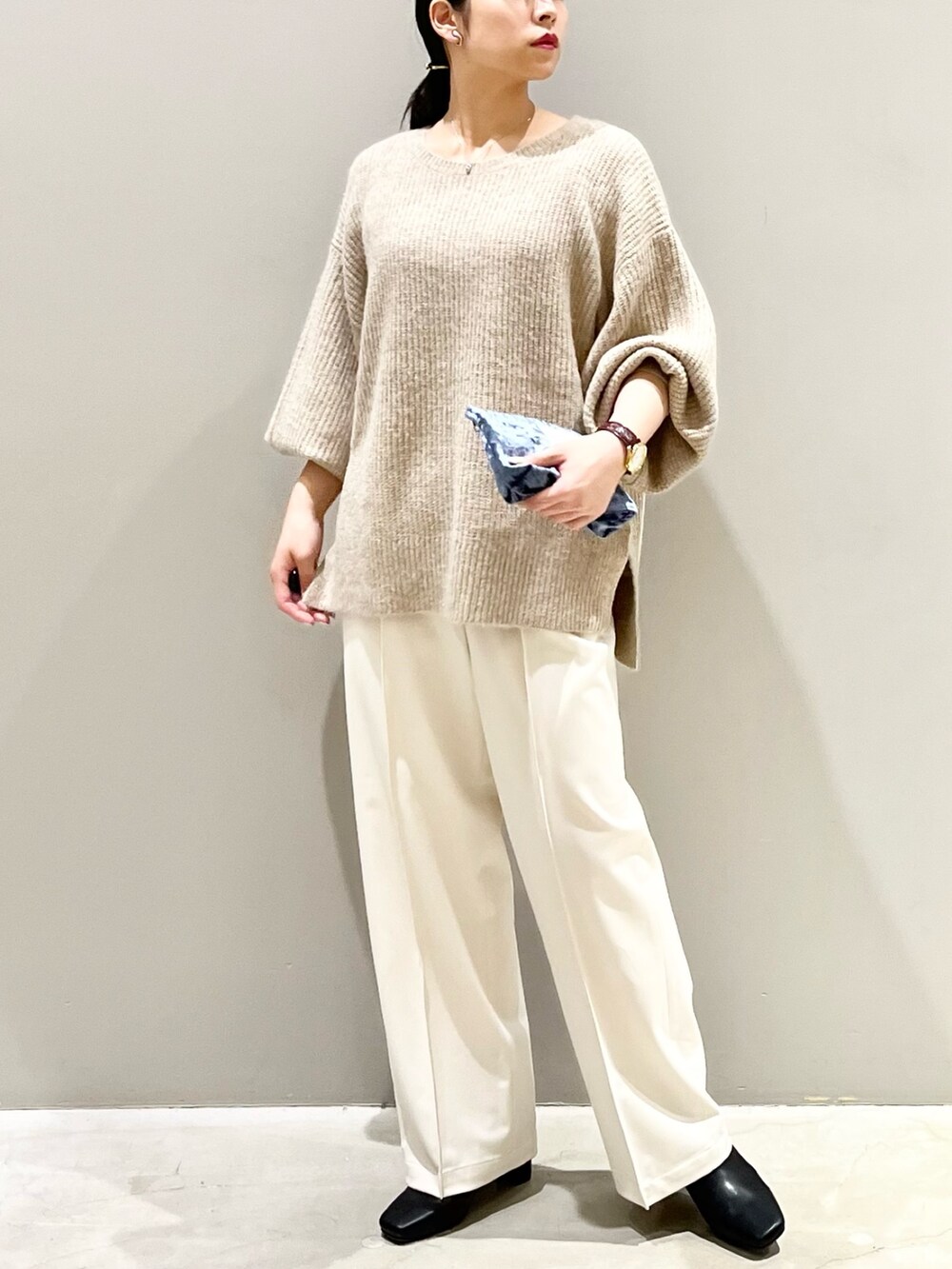 ベージュ系のニット/セーター、ホワイト系のスラックス、ブラック系のブーツを着用したレディースの秋コーディネートの3枚目の写真