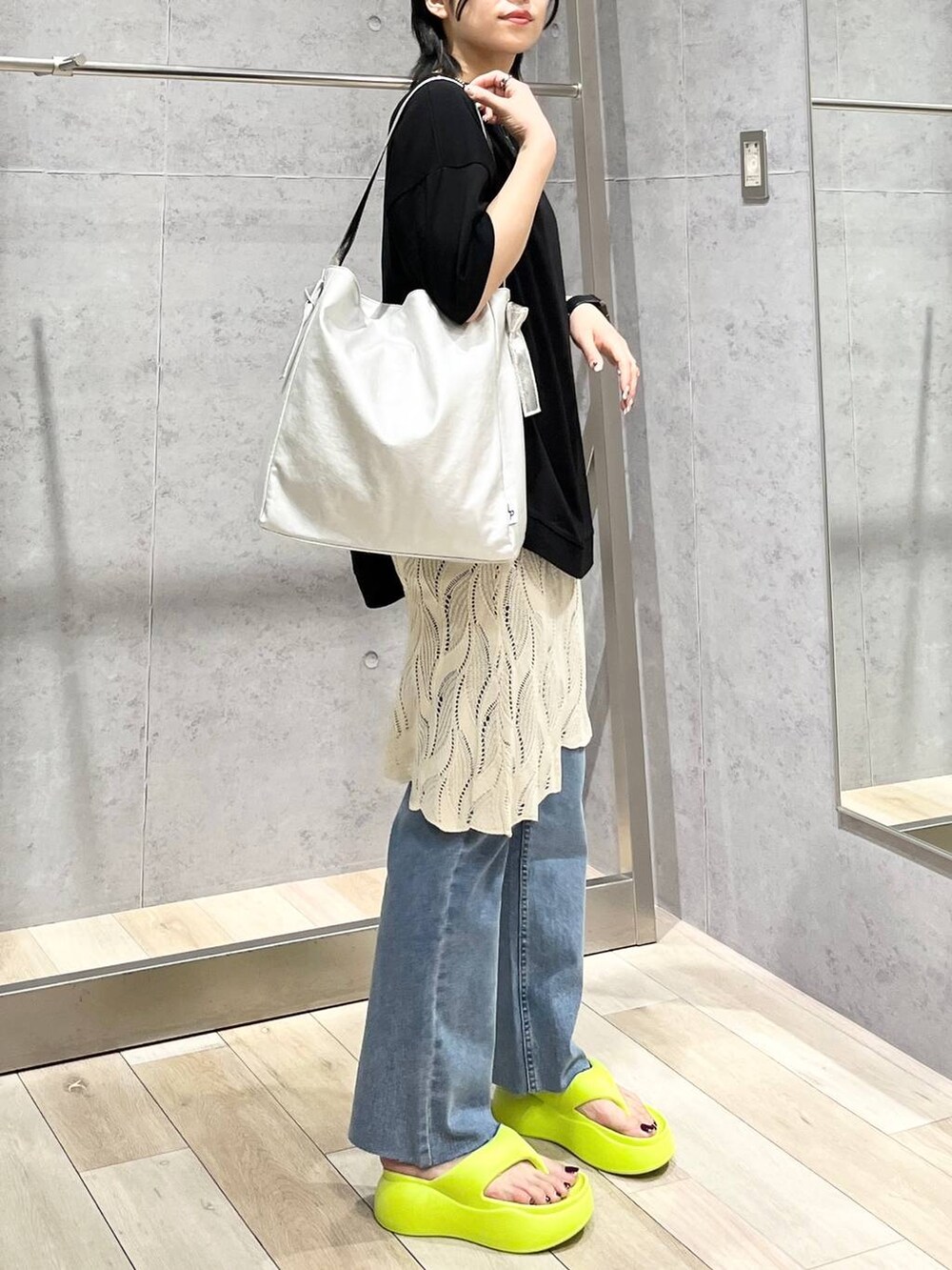 イエロー系のサンダル、グレー系のショルダーバッグ、ブルー系のデニムパンツを着用したレディースの春コーディネートの5枚目の写真