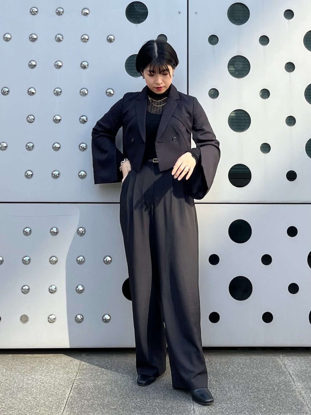 ブラック系のスラックス、ブラック系のブーツ、ブラック系のトップスを着用したレディースの冬コーディネートの2枚目の写真