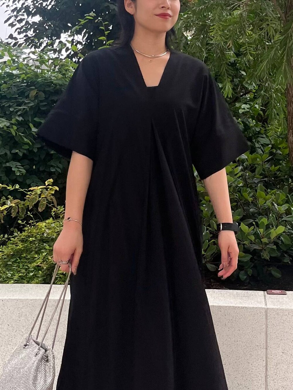 シルバー系のショルダーバッグ、ブラック系のワンピース、シルバー系のネックレスを着用したレディースの夏コーディネートの5枚目の写真