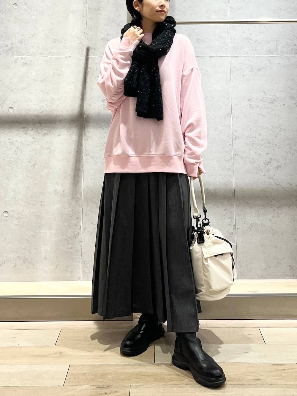 ホワイト系のショルダーバッグ、ピンク系のスウェット、ブラック系のブーツを着用したレディースの秋コーディネートの2枚目の写真