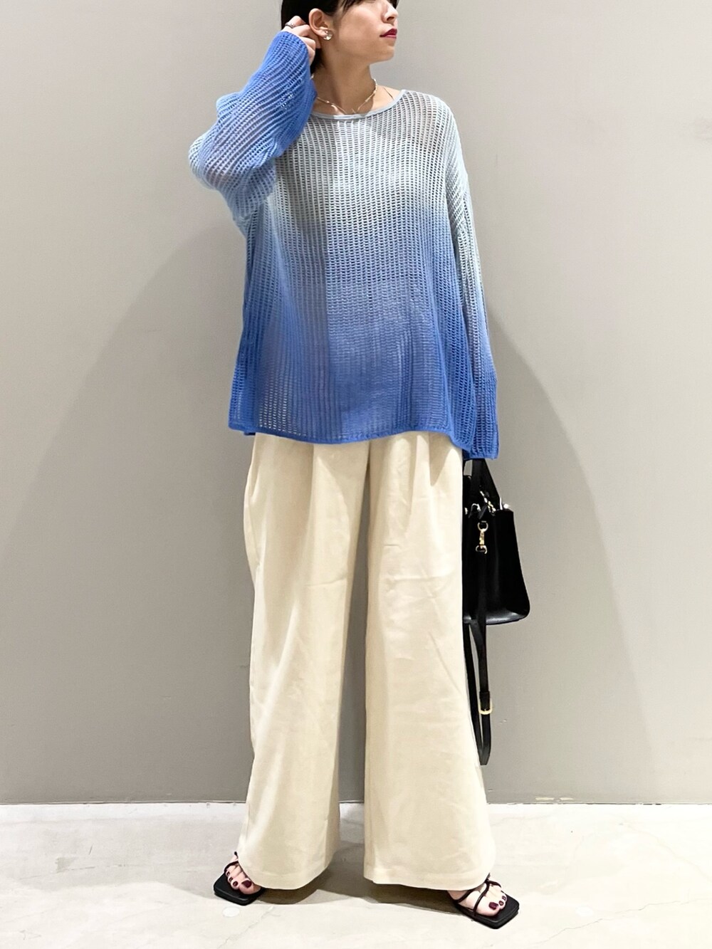 ブルー系のニット/セーター、ブラック系のショルダーバッグ、ブラック系のサンダルを着用したレディースの春コーディネートの3枚目の写真