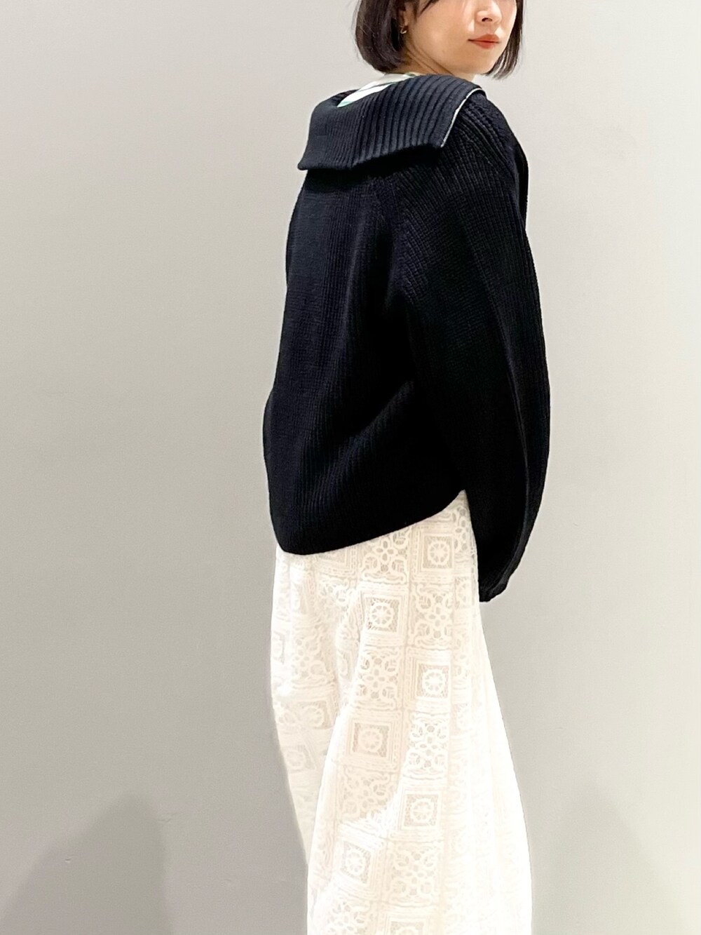 ブラウン系のショルダーバッグ、ホワイト系のスカート、ブラック系のブーツを着用したレディースの冬コーディネートの4枚目の写真