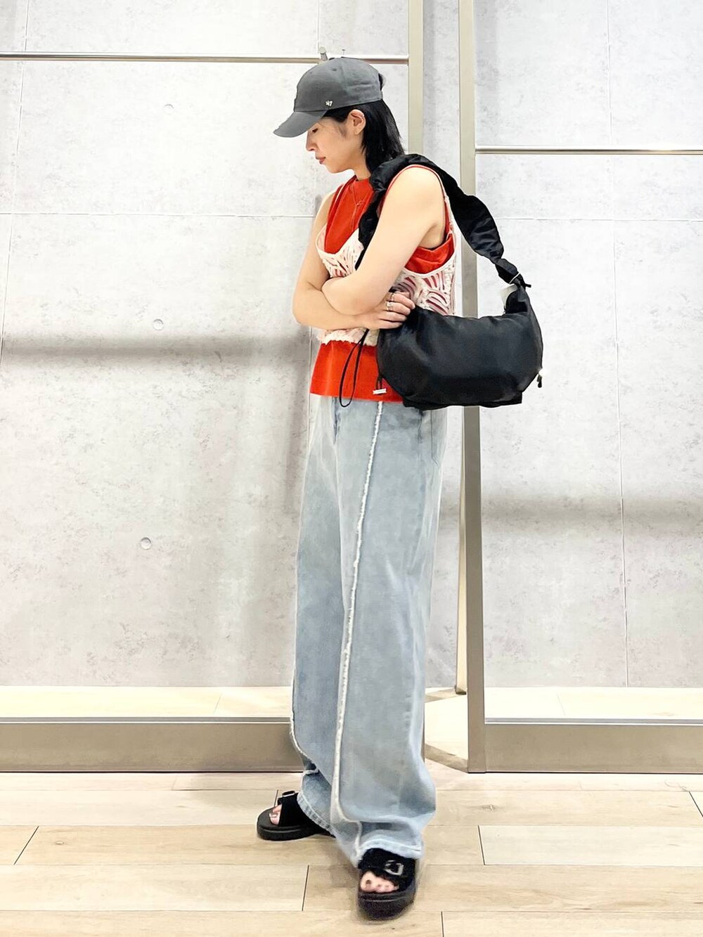 オレンジ系のタンクトップ、ブラック系のショルダーバッグ、ブルー系のデニムパンツを着用したレディースの夏コーディネートの2枚目の写真