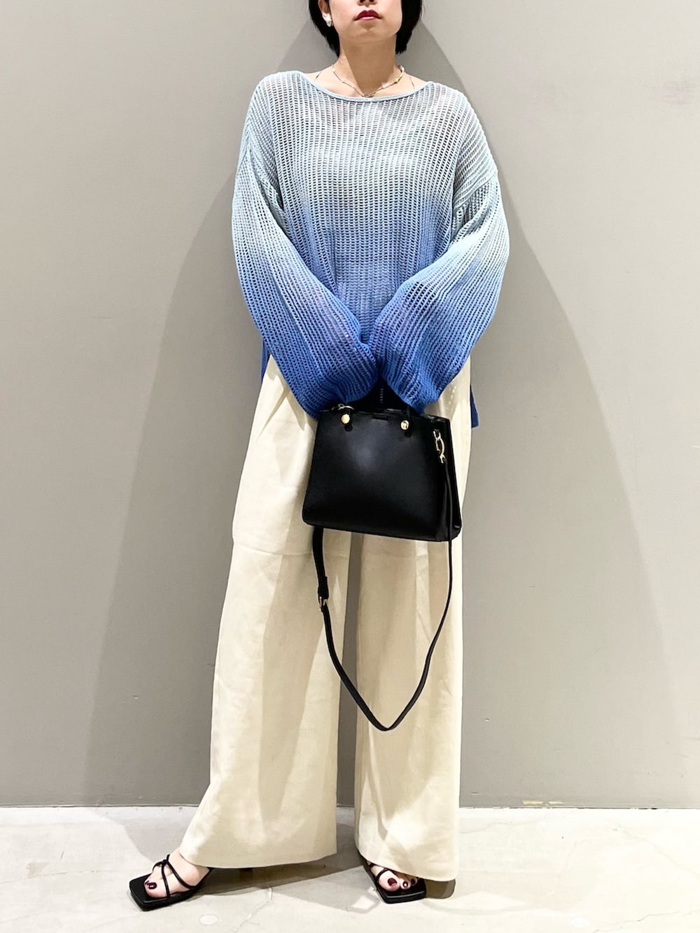ブルー系のニット/セーター、ブラック系のショルダーバッグ、ブラック系のサンダルを着用したレディースの春コーディネートの2枚目の写真