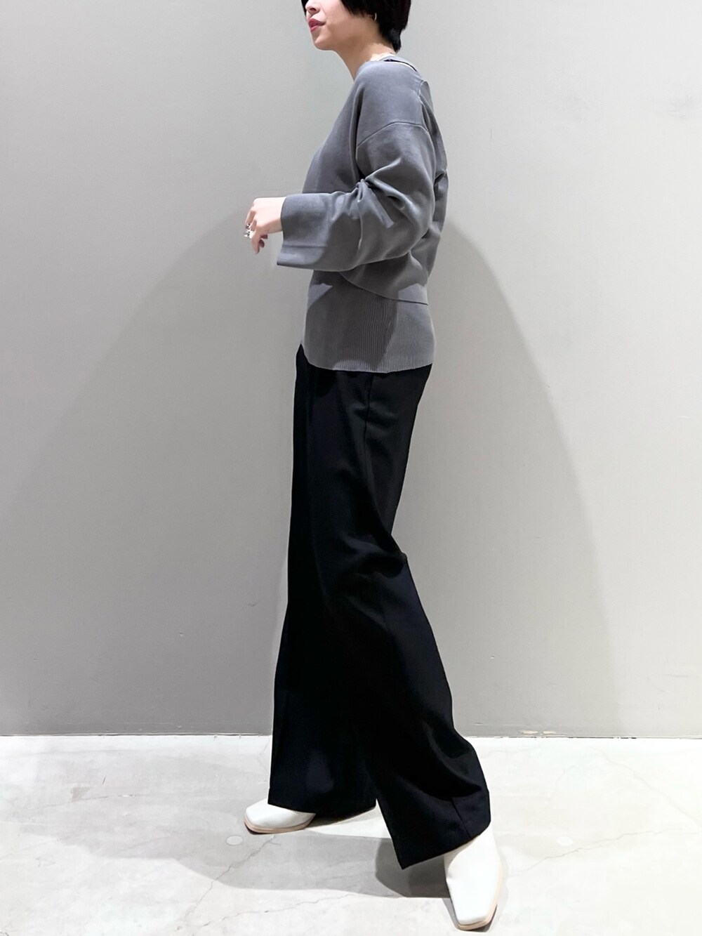 グレー系のニット/セーター、ブラック系のパンツ、ホワイト系のシューズを着用したレディースの春コーディネートの8枚目の写真