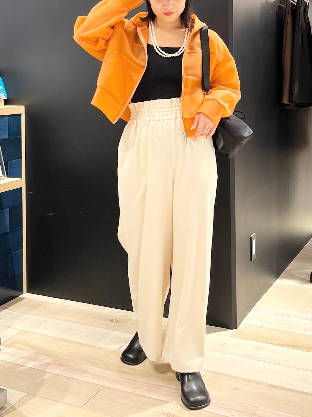 ホワイト系のタンクトップ、ブラック系のショルダーバッグ、オレンジ系のパーカーを着用したレディースの秋コーディネートの2枚目の写真