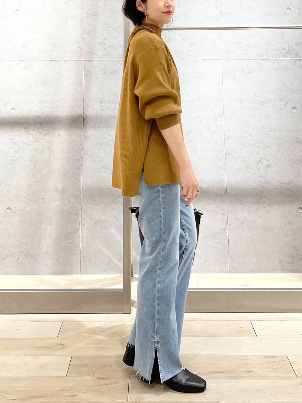 ブラウン系のニット/セーター、ブルー系のデニムパンツ、ベージュ系のショルダーバッグを着用したレディースの秋コーディネートの6枚目の写真