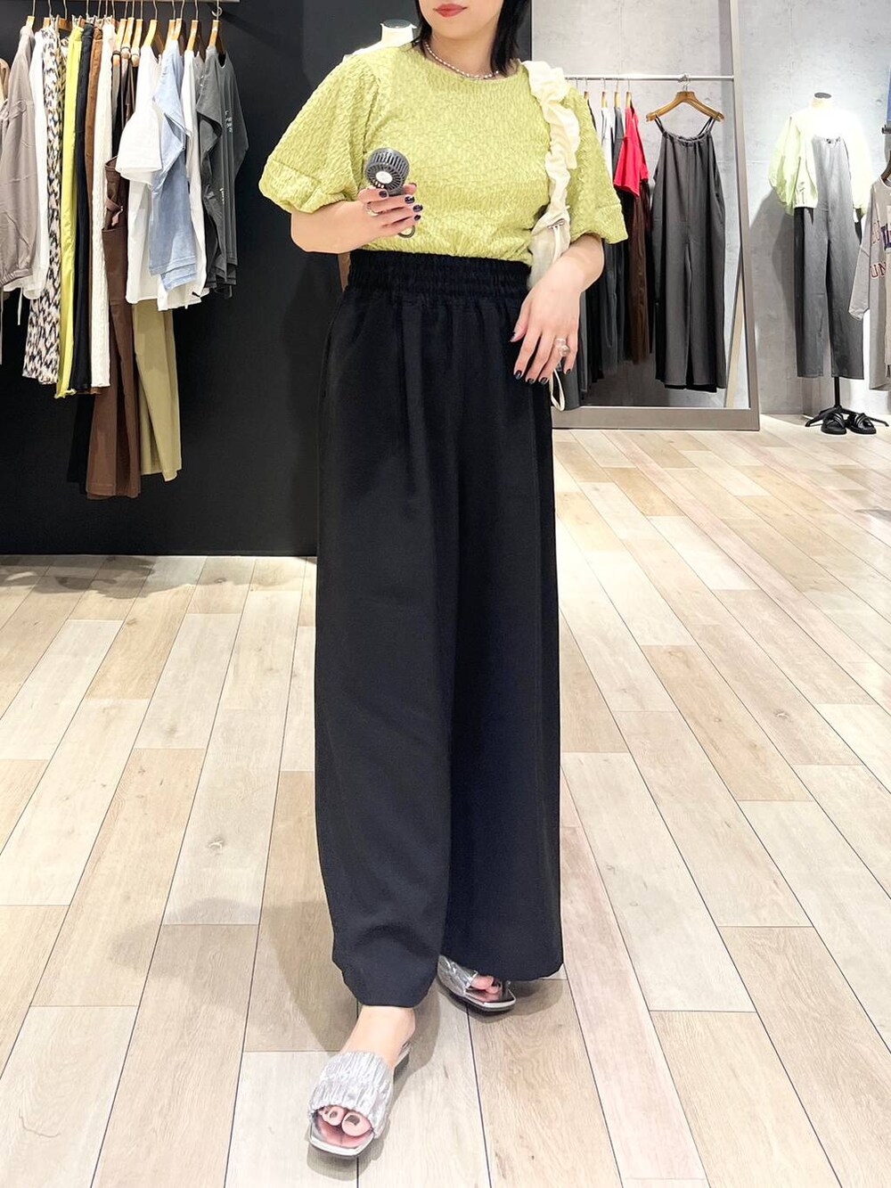 ブラック系のその他パンツ、グリーン系のTシャツ/カットソー、ホワイト系のショルダーバッグを着用したレディースの夏コーディネートの4枚目の写真