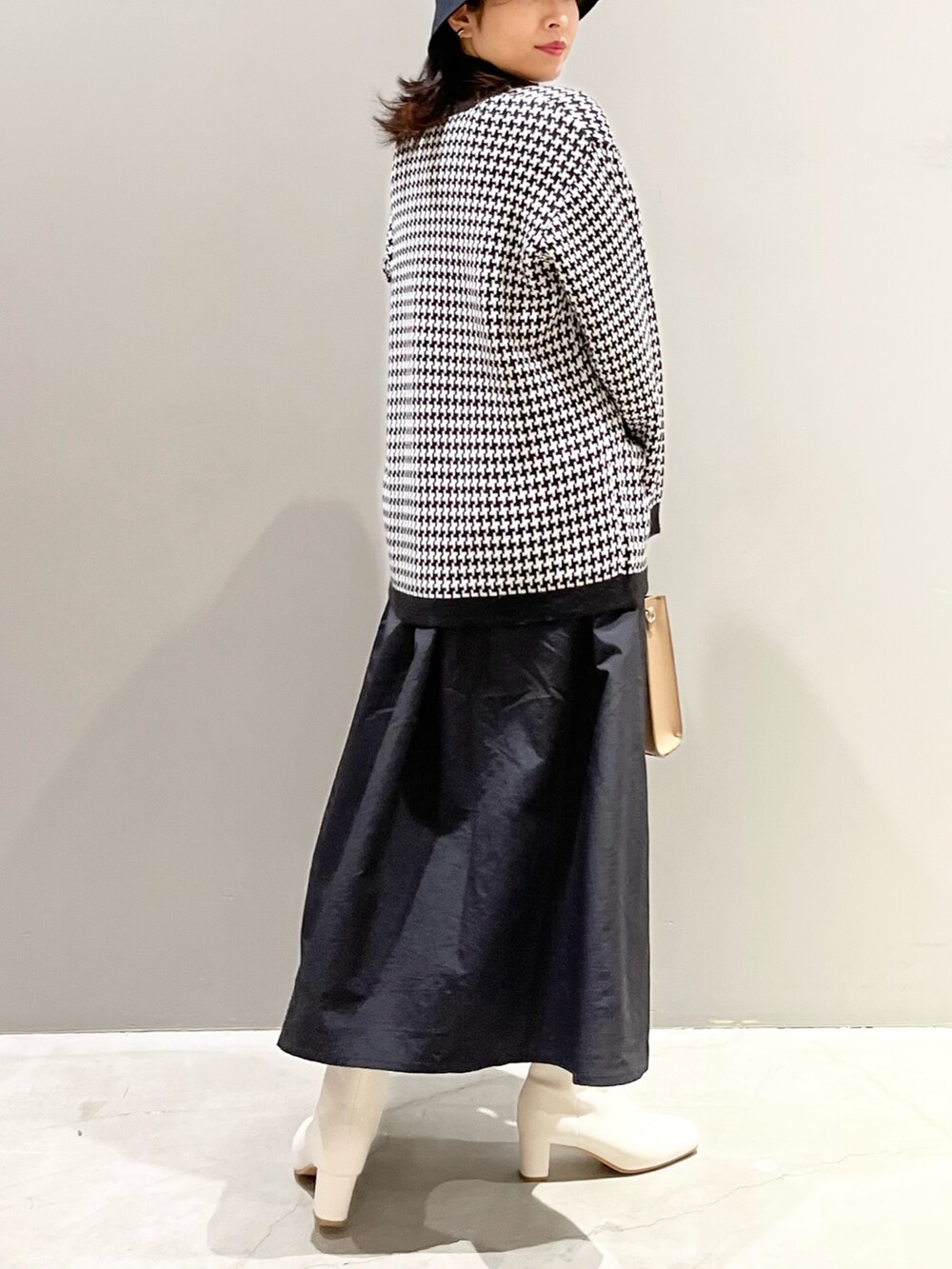 ベージュ系のショルダーバッグ、ホワイト系のブーツ、ブラック系のワンピースを着用したレディースの冬コーディネートの2枚目の写真