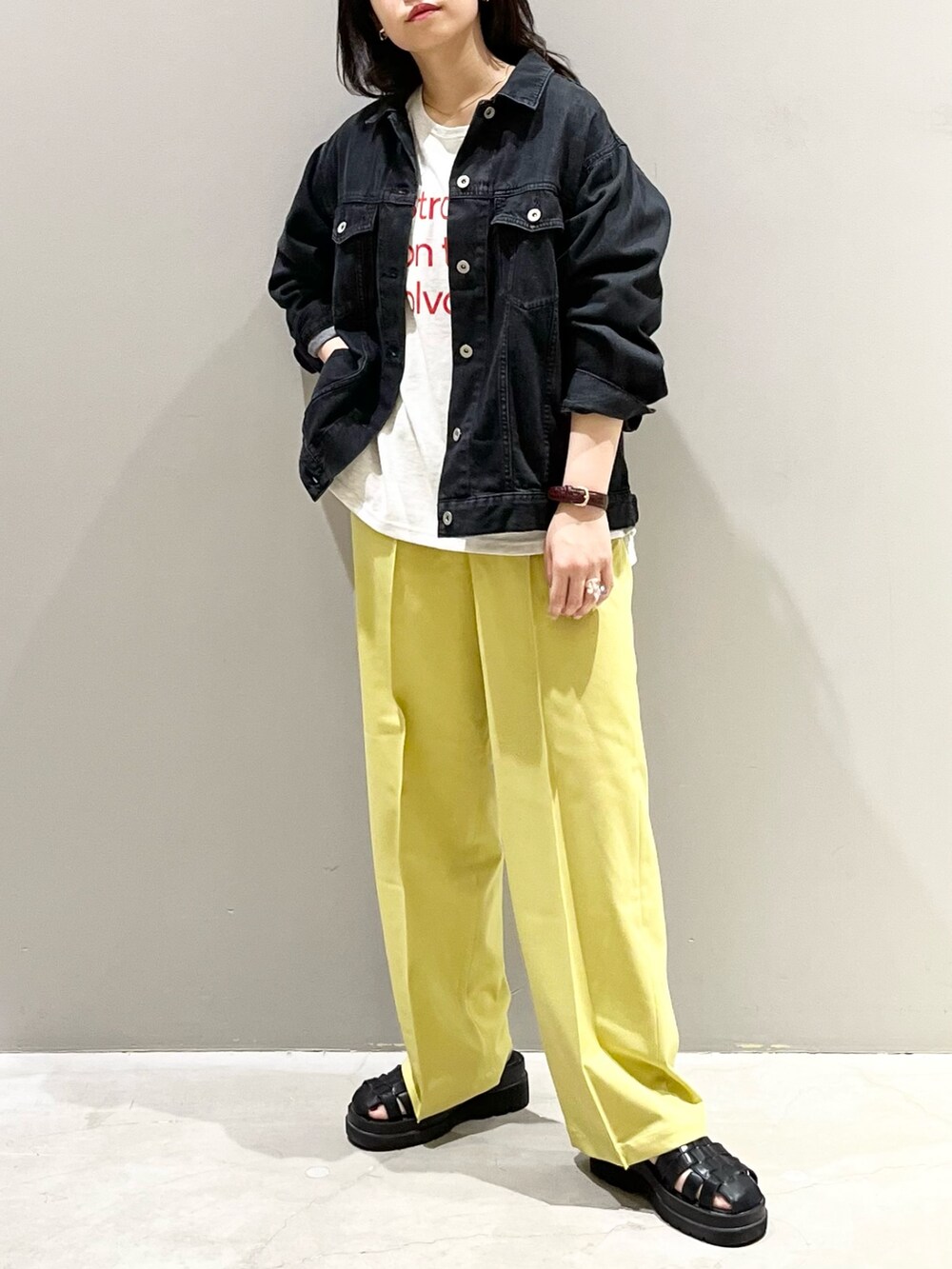 イエロー系のスラックス、ブラック系のサンダル、ベージュ系のTシャツ/カットソーを着用したレディースの秋コーディネートの2枚目の写真