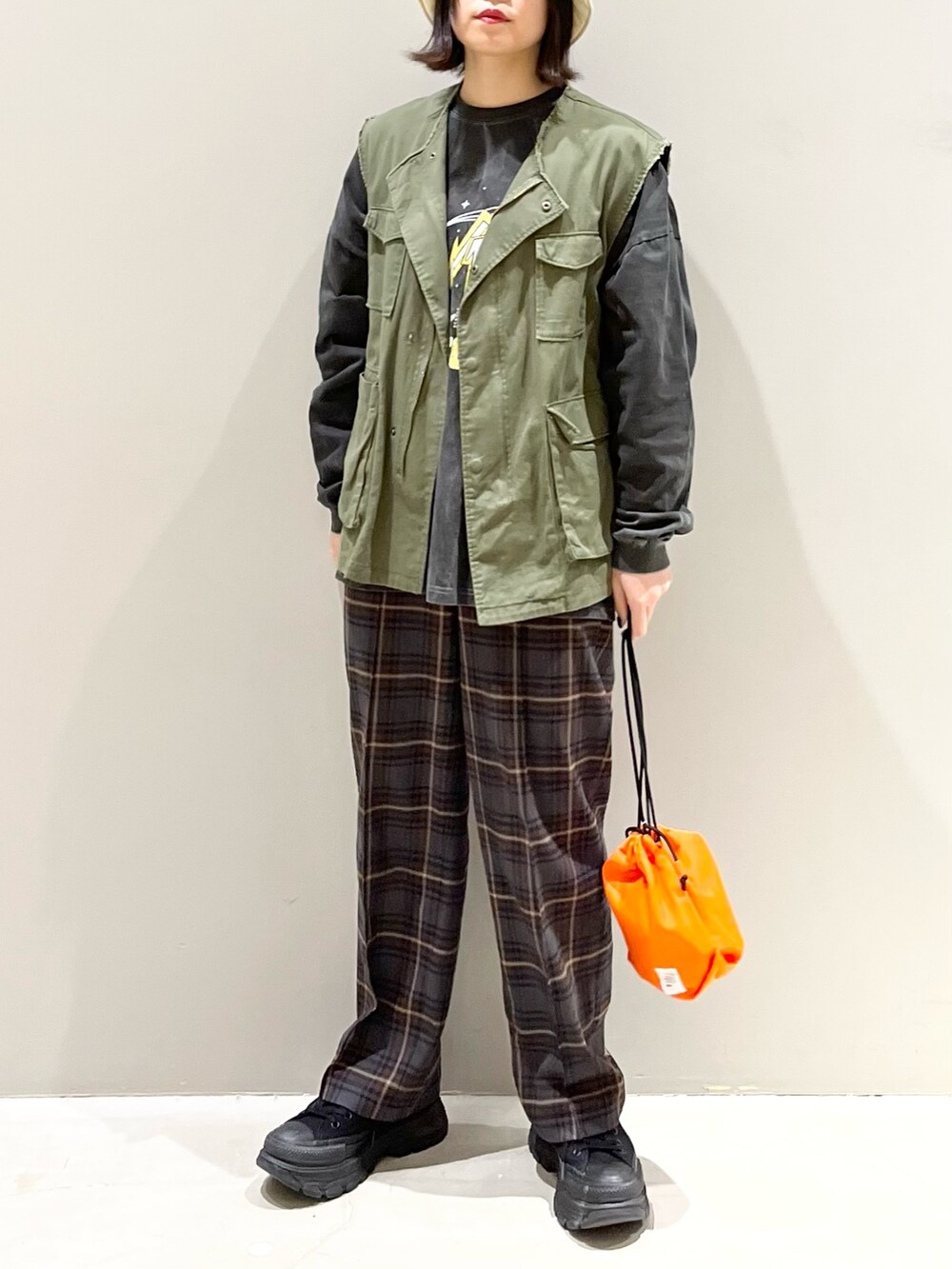 ブラウン系のスラックス、ブラック系のスニーカー、グリーン系のジャケット/アウターを着用したレディースの春コーディネートの2枚目の写真