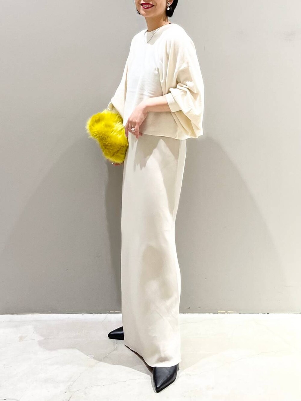 ブラック系のキャミソール、ホワイト系のニット/セーター、イエロー系のハンドバッグを着用したレディースの秋コーディネートの3枚目の写真