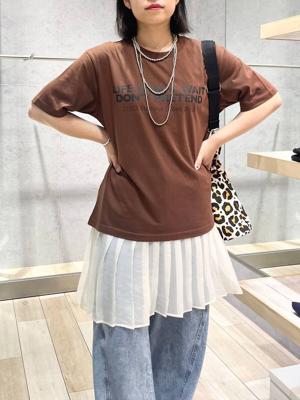 ブルー系のデニムパンツ、ブラック系のサンダル、シルバー系のネックレスを着用したレディースの夏コーディネートの2枚目の写真