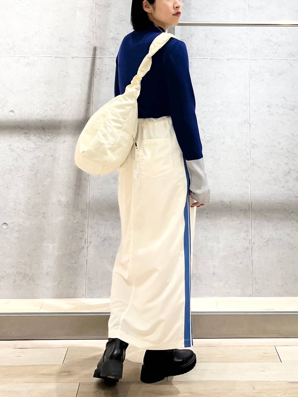 ブラック系のブーツ、ホワイト系のショルダーバッグ、ホワイト系のスカートを着用したレディースの冬コーディネートの7枚目の写真