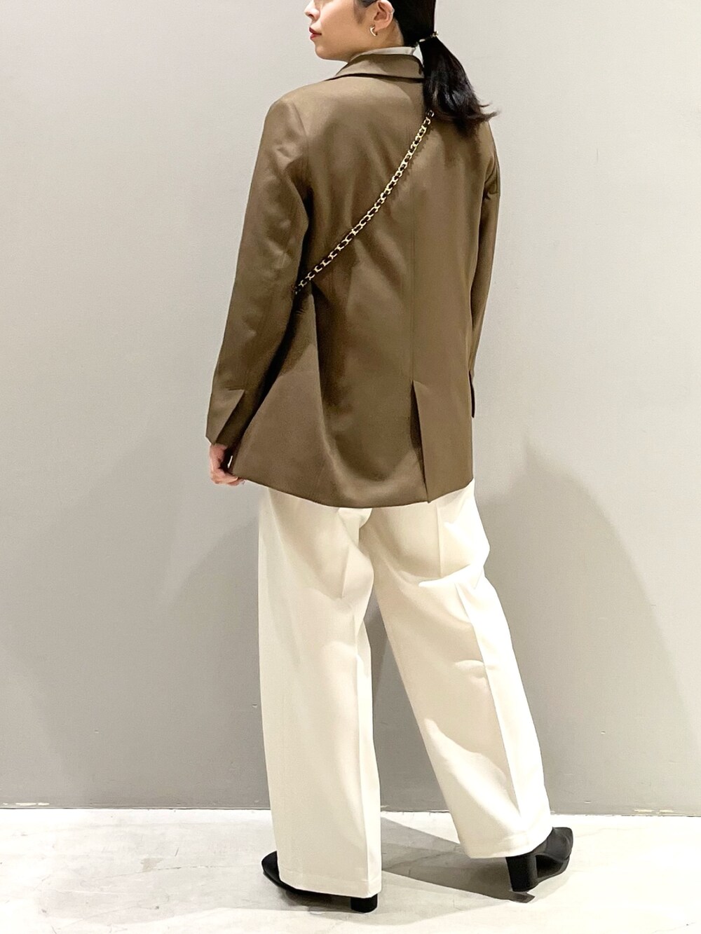 ホワイト系のスラックス、ブラック系のブーツ、ブラック系のバッグを着用したレディースの秋コーディネートの4枚目の写真