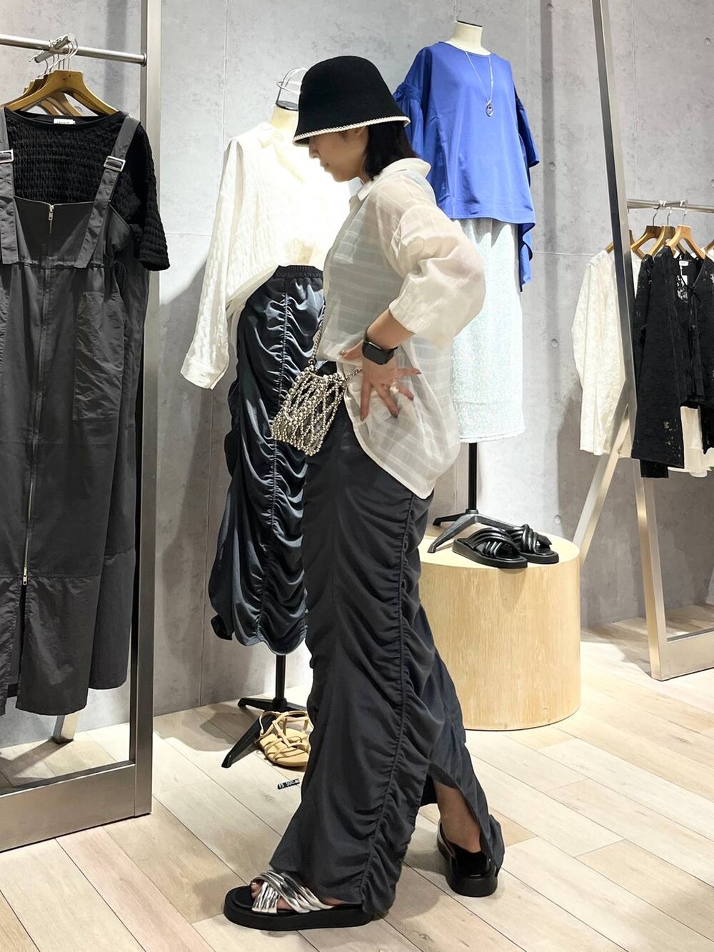 グレー系のスカート、シルバー系のサンダル、ブルー系のタンクトップを着用したレディースの夏コーディネートの3枚目の写真