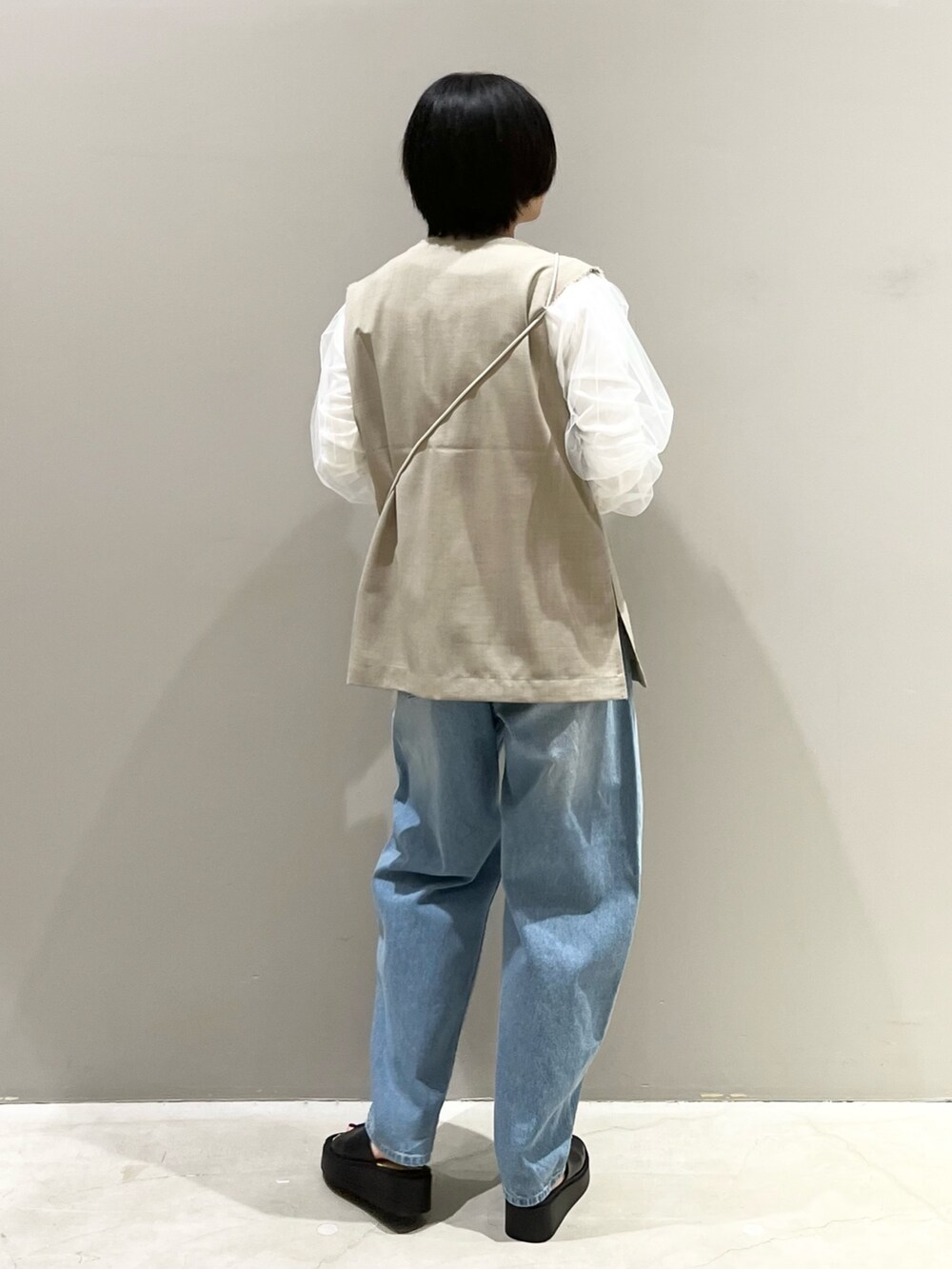 ブルー系のデニムパンツ、ホワイト系のサンダル、ブラック系のバッグを着用したレディースの春コーディネートの3枚目の写真