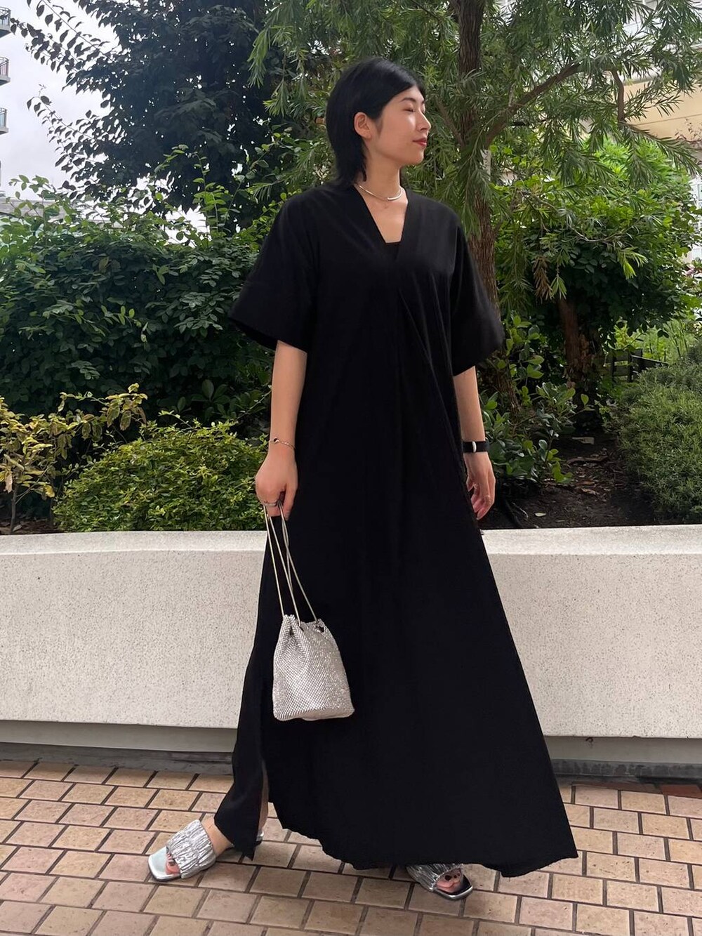 シルバー系のショルダーバッグ、ブラック系のワンピース、シルバー系のネックレスを着用したレディースの夏コーディネートの2枚目の写真