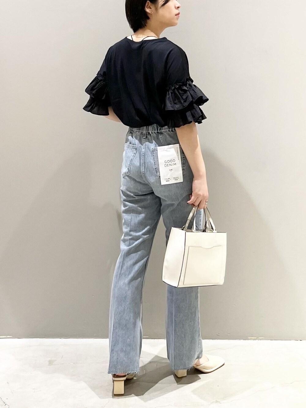 ブルー系のデニムパンツ、ホワイト系のショルダーバッグ、ホワイト系のパンプスを着用したレディースの夏コーディネートの4枚目の写真