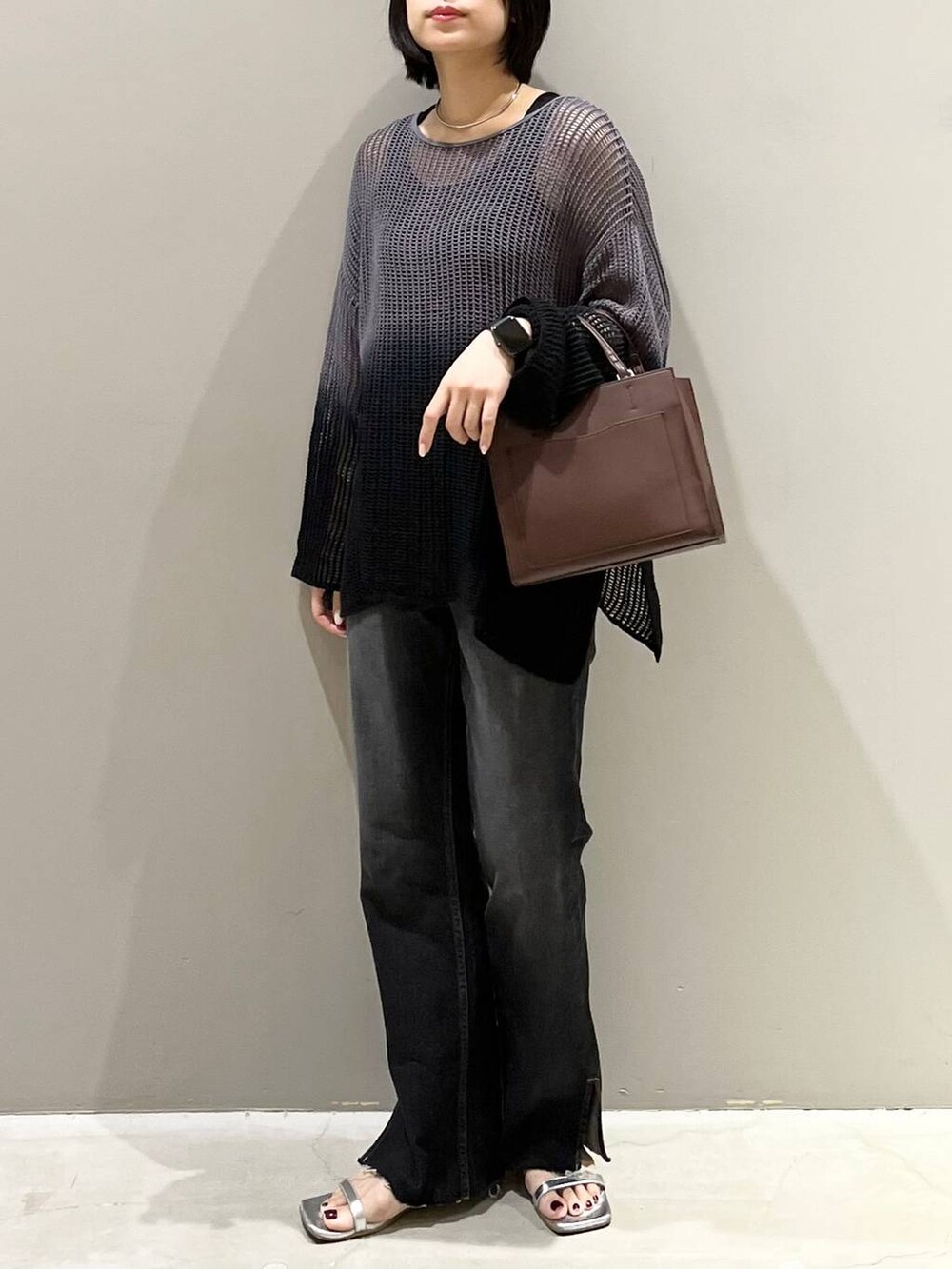 ブラック系のニット/セーター、シルバー系のサンダル、ブラック系のデニムパンツを着用したレディースの夏コーディネートの2枚目の写真