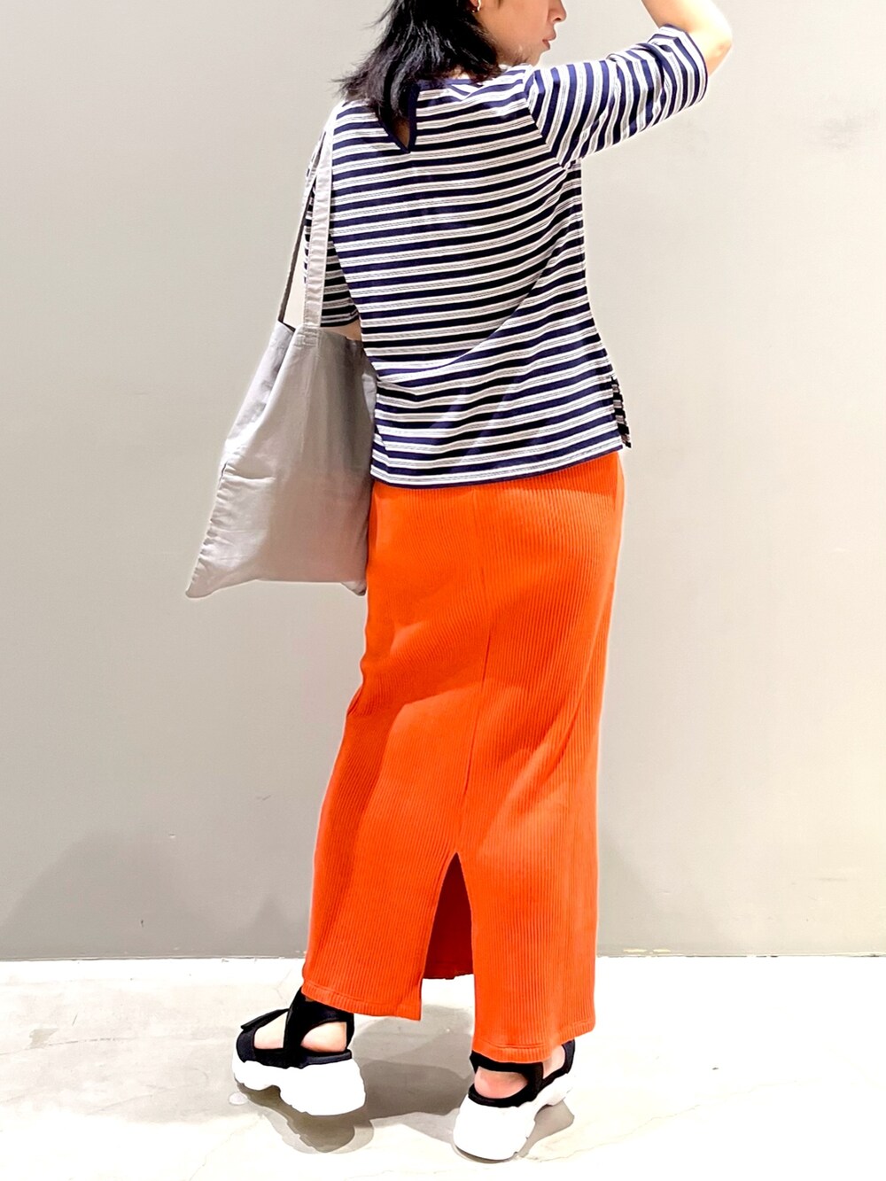 ブラック系のサンダル、オレンジ系のスカート、グレー系のトートバッグを着用したレディースの秋コーディネートの3枚目の写真