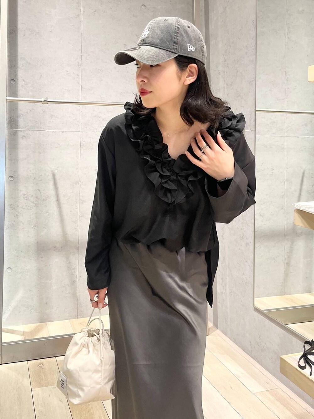 グレー系のスカート、ホワイト系のショルダーバッグ、ブラック系のキャップを着用したレディースの春コーディネートの6枚目の写真